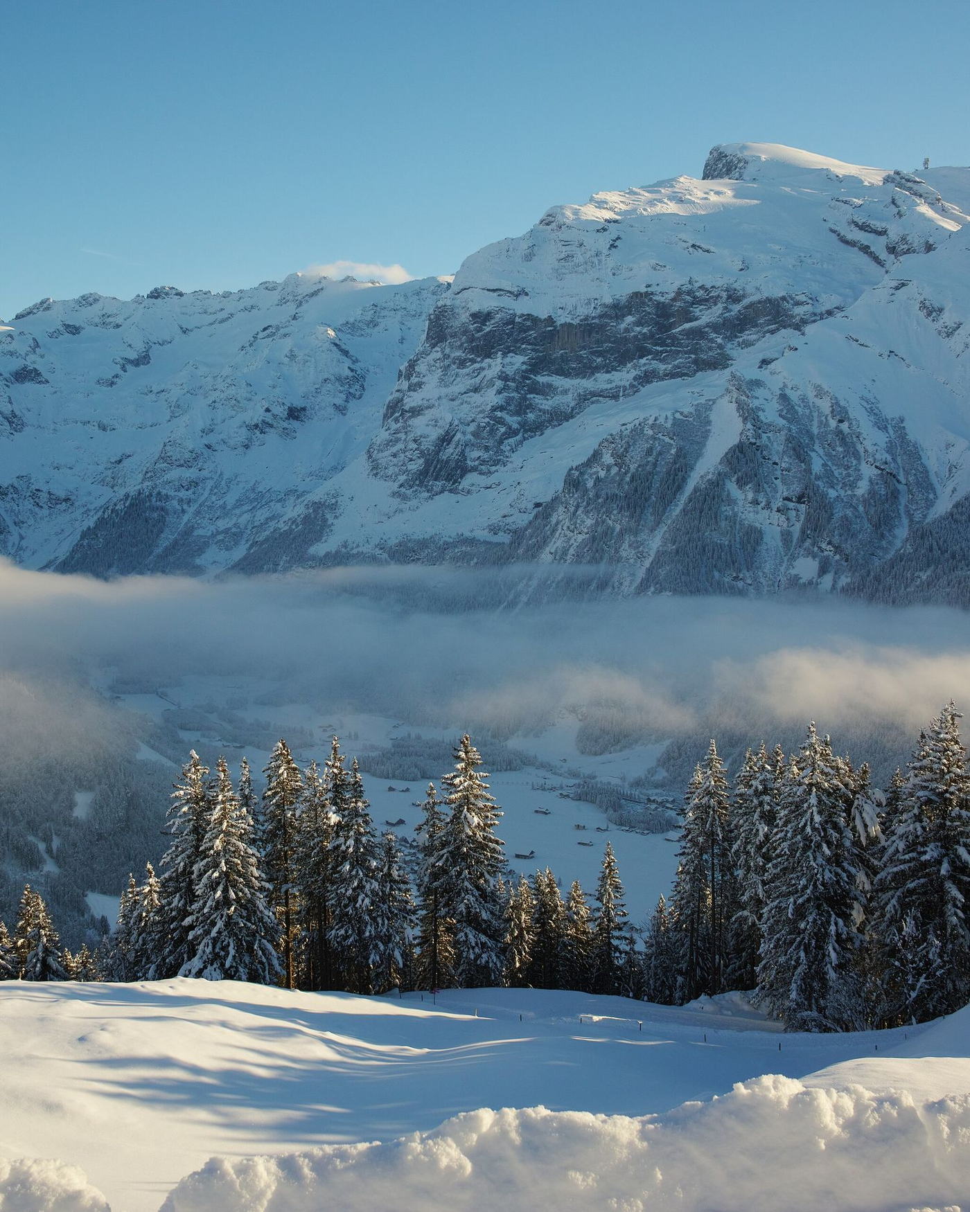 The Engelberg valley in winter, seen from the slopes above the village with the Titlis massif behind.