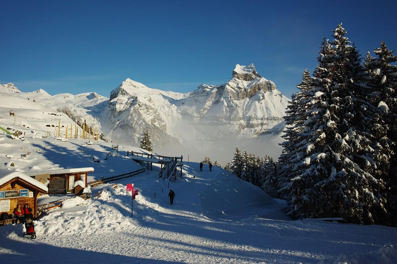 Winter walkers on a groomed path above Engelberg with the Hahnen peak in the background.