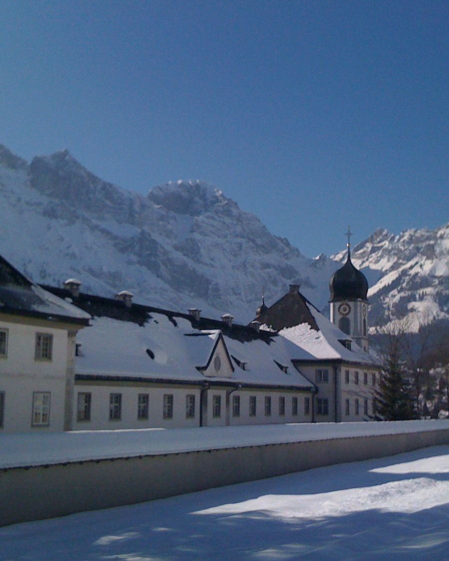Engelberg monastery and village rooftops under snow, with the mountains rising behind.